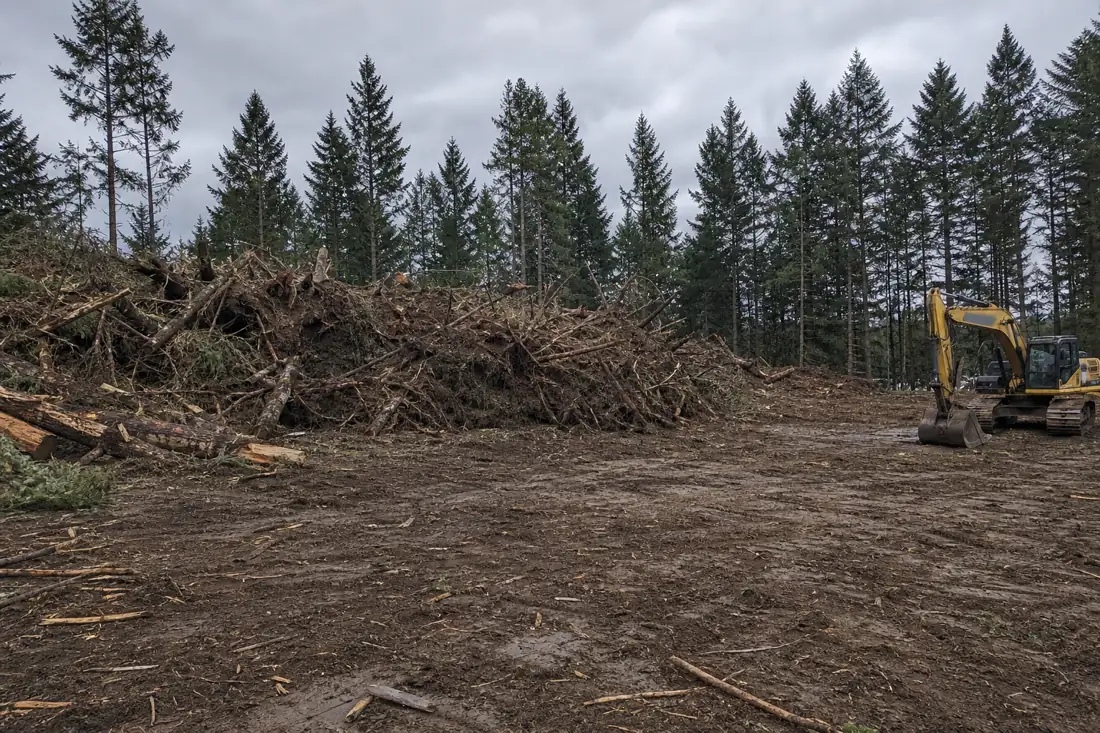 Rural Hillsboro lot fully cleared of trees and brush with debris pile and excavator
